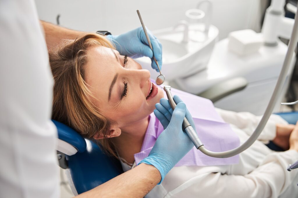 Doctor taking care of calm lady teeth with drill machine